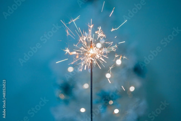 Fototapeta Beautiful sparklers made of sparklers on a New Year's bokeh background, on a blue background, Christmas mood, glitter, holiday background.
