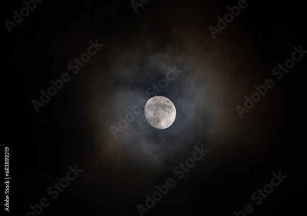 Fototapeta Moon in the night sky with a halo of colors from the clouds