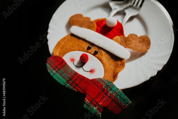 Fototapeta Preparation for the festive feast: transformation of the Christmas table. Top view photo of a plate, cutlery, napkin on a black background with an advertising area. Copy space for text