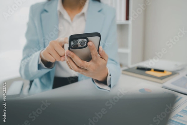 Fototapeta An entrepreneur is talking on the phone with a company customer, Businesswoman is sitting and working in the office, Recording various information on paper,