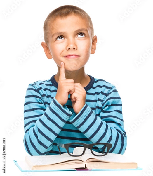 Fototapeta Young boy is daydreaming while reading book
