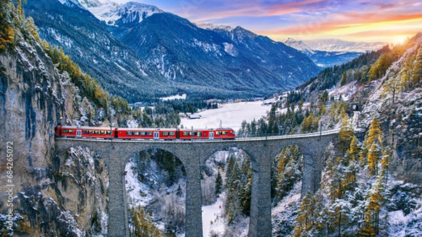 Fototapeta Aerial view of Train passing through famous mountain in Filisur, Switzerland. Landwasser Viaduct world heritage with train express in Swiss Alps snow winter scenery.