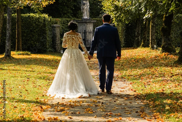 Obraz bride and groom walking in park in autumn