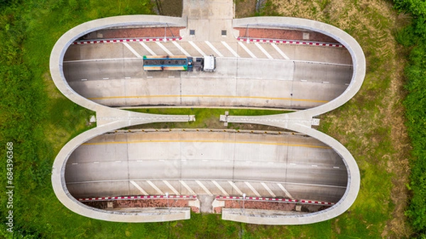 Fototapeta Aerial view of wildlife overpass over highway,  new road with tunnel in green summer mountains.