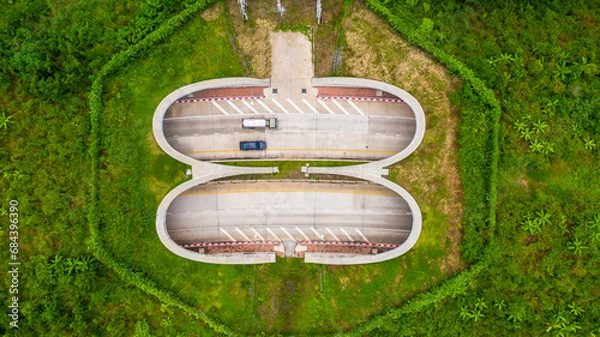 Fototapeta Aerial view of wildlife overpass over highway,  new road with tunnel in green summer mountains.