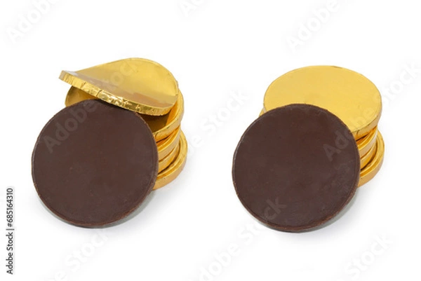 Obraz Stacks of chocolate coins in gold packaging with one dark chocolate coin unfolded in front view. Photo isolated on white background.
