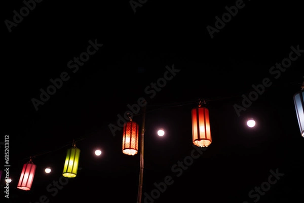 Fototapeta a paper lantern floats on a dark background.