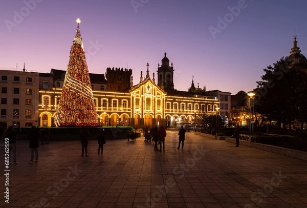 Fototapeta Portuguese Christmas lights decoration with an enormous tree in Braga city center, Portugal. People taking photos with smartphones of the christmas decorations