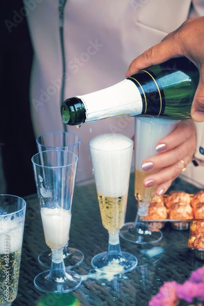 Obraz Pouring champagne into a glass for guests at a wedding