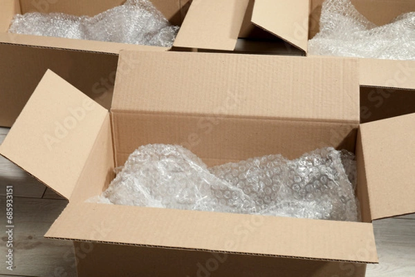 Fototapeta Many open cardboard boxes with bubble wrap on white wooden floor