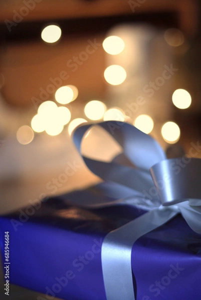 Obraz Wrapped present closeup in front of twinkling lights