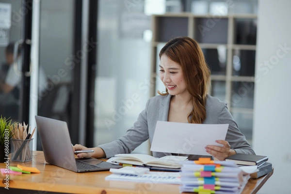 Fototapeta Businesswoman working with stack of documents papers and laptop sitting at office desk.