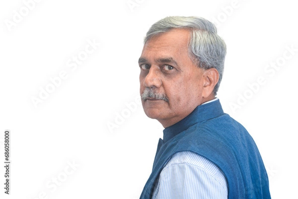 Obraz Senior Indian businessman or executive in a light blue shirt and dark sleveless jacket looking left over his shoulder