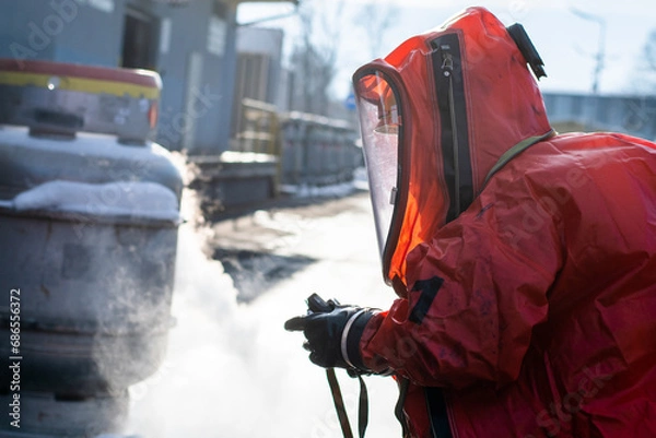 Fototapeta Firefighters in protective chemical HAZMAT suits stop the leak of the dangerous substance ethylene oxide from the tank