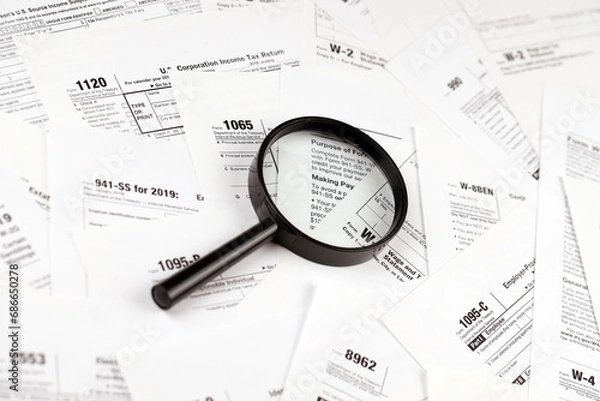 Fototapeta Magnifying glass lying over heap of paper documents. Investigation and financial audit concept