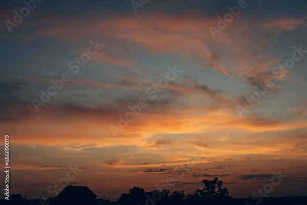 Fototapeta An image of a beautiful and unusual sunset. The ever-changing sky. An inspiring observation of clouds and the surrounding natural world. Can be used as banner background, wallpaper.