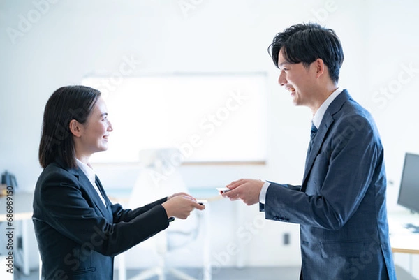 Fototapeta オフィスで名刺交換する若い男女ビジネスマン