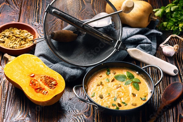 Fototapeta bowl of pumpkin vegetarian cream soup on dark wooden background with ingredients.