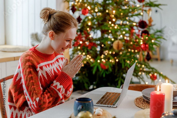 Obraz young blonde woman sits at table in kitchen with Christmas tree, gets unexpected great news, feels elation and thrilled. unbelievable and astonishing information