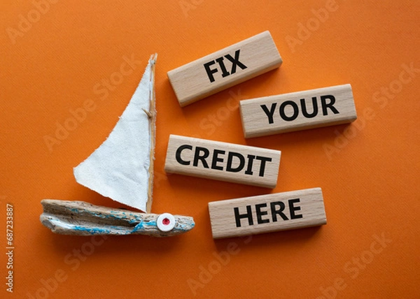 Fototapeta Fix your credit here symbol. Concept words Fix your credit here on wooden blocks. Beautiful orange background with boat. Business and Fix your credit here concept. Copy space.