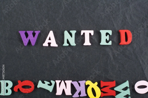 Fototapeta WANTED word on black board background composed from colorful abc alphabet block wooden letters, copy space for ad text. Learning english concept.