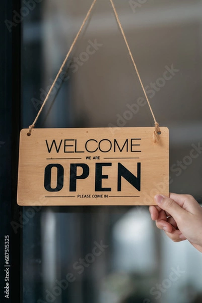 Fototapeta Successful small business owner holding open sign.