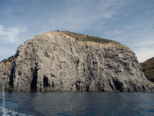 Fototapeta Weathered seaside rock face texture with parts of green and blue water. Aged volcanic stone wall surface background pattern with cracks and scratches. Banner. Ischia Island, Italy.