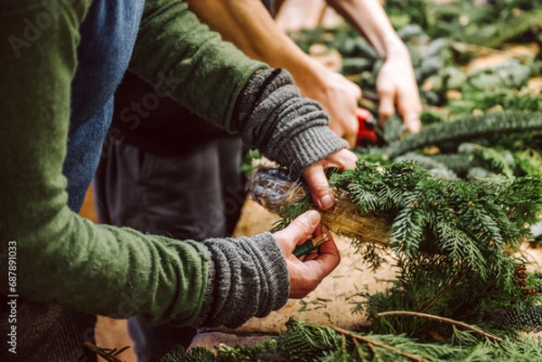 Fototapeta Hände von zwei Menschen halten Draht, Zange und Adventskranz. Mensch bastelt einen weihnachtlichen Adventskranz.
