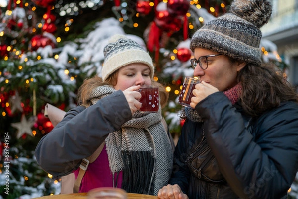 Fototapeta Two Friends Enjoying Red Glühwein by the Christmas Tree