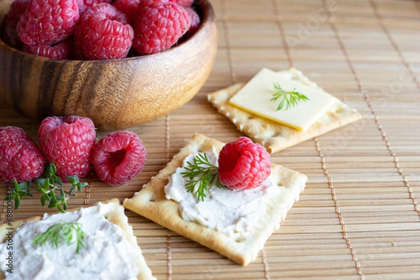 Obraz Vegan cream cheese on top of a salty cracker with raspberries and fresh herbs. Vegan food concept.