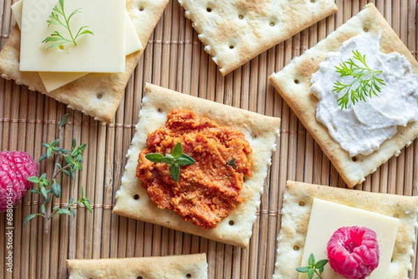 Obraz Various kind of salty crackers with vegan meat and vegan cream cheese decorated with fresh herbs and raspberries. Vegan food concept.