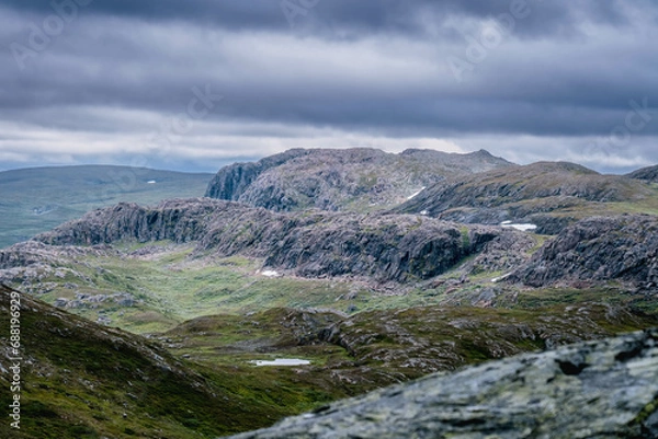 Fototapeta Scenic view at high altitude mountain terrain in Scandinavian Mountains range. Heavy dark blue clouds. Hiking destination in Norway, Krutvatnet area