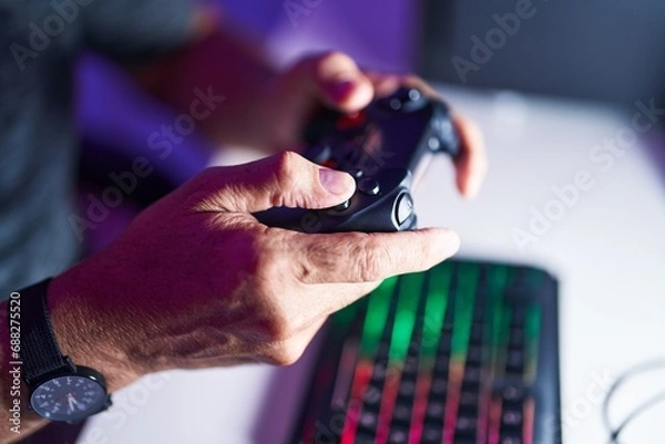 Fototapeta Middle age grey-haired man playing video game using joystick at gaming room