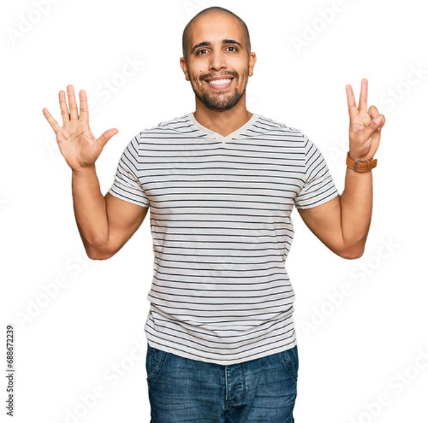 Obraz Hispanic adult man wearing casual clothes showing and pointing up with fingers number seven while smiling confident and happy.