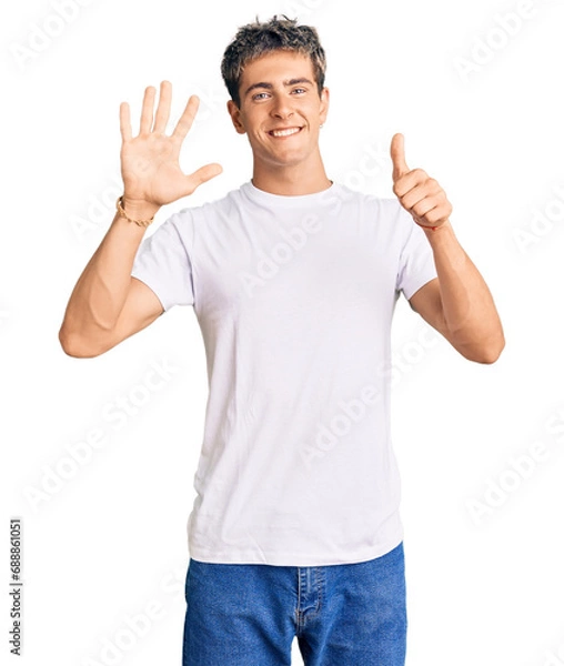 Fototapeta Young handsome man wearing casual white tshirt showing and pointing up with fingers number six while smiling confident and happy.