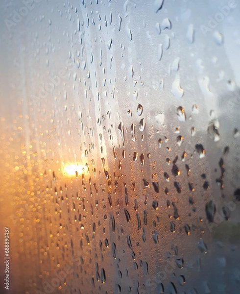 Fototapeta Closeup of Beautiful Rain drop on the window glass after the rain with golden light sunset blurred bokeh background at Thailand.