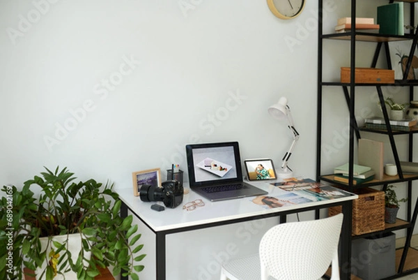 Fototapeta Laptop, digital camera and printed photos on desk of photographer