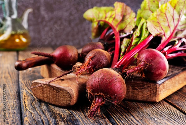 Fototapeta fresh beets on cutting board, set on wooden table viewed from above