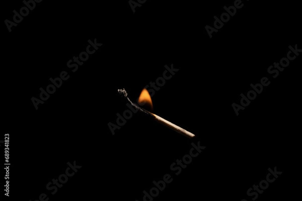 Fototapeta Lit falling match on a black background.
