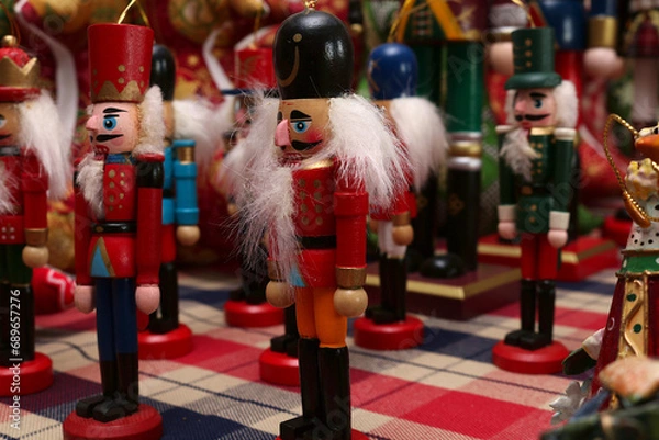 Fototapeta Close up of a nut cracker soldier Christmas decoration with more soldiers in soft focus behind.
