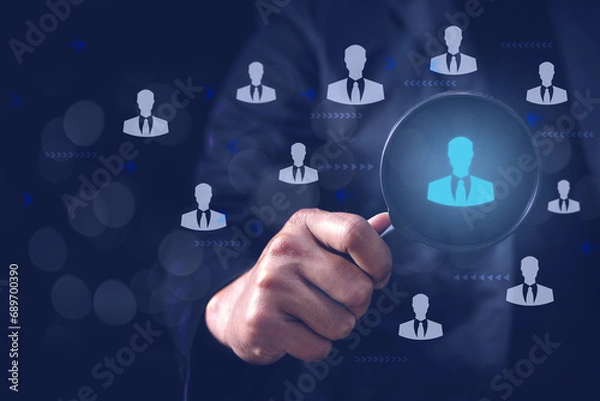 Fototapeta Businessman holding magnifier for searching to human icons for recruitment and human development, customer focus target group concept. Human Resource Management or HRM concept.