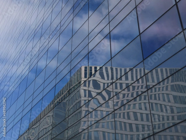 Fototapeta reflection of an office building and a cloudy sky in a glass facade