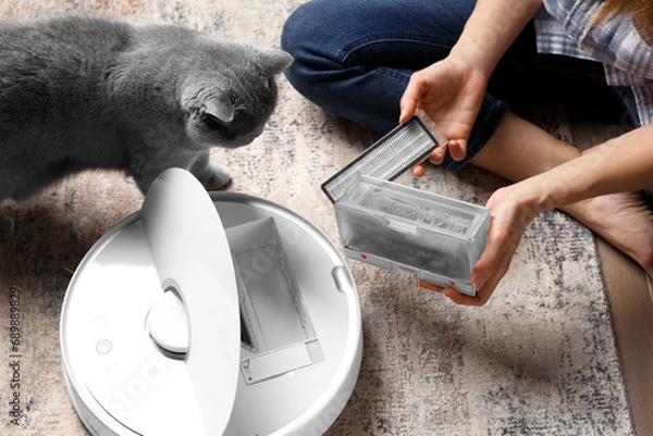 Fototapeta The container of the robot vacuum cleaner in female hands, the dust container of the is full of wool
