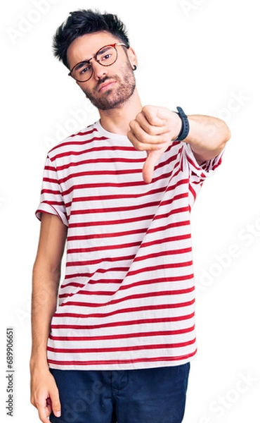 Fototapeta Young hispanic man wearing casual clothes looking unhappy and angry showing rejection and negative with thumbs down gesture. bad expression.