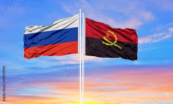 Fototapeta Russia and angola two flags on flagpoles and blue sky.