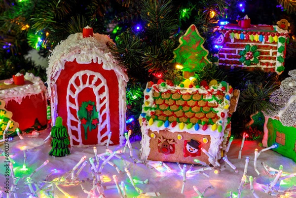 Fototapeta Christmas tree and colorful garlands decorate this gingerbread house.