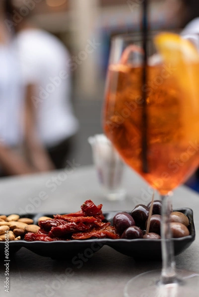 Obraz Aperol Spritz in outdoor cafe,  snacks with sun-dried tomatoes, olives and nuts