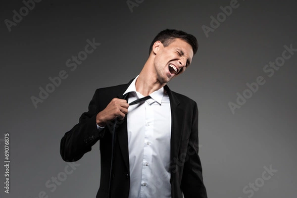 Obraz Man loosing tie on grey background.
