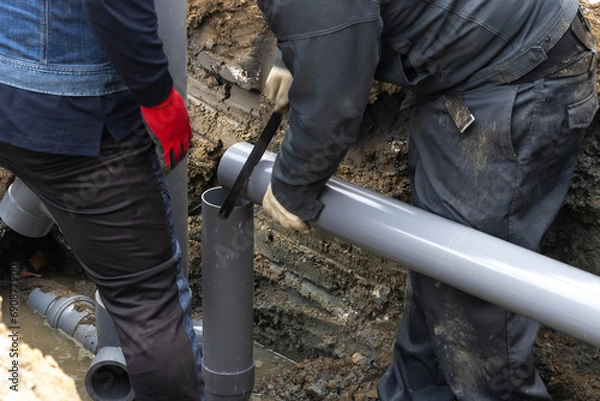 Obraz 住宅の排水を下水道につなげる配管工事する人物
