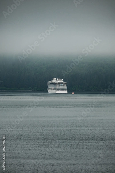Fototapeta Luxury cruiseship cruise ship liner Orion and tender life boat in Hoonah Icy Strait Point Bay, Alaska with low hanging clouds and nature landscape scenery